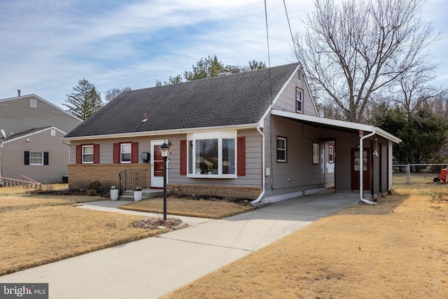 view of front of home featuring an attached carport, roof with shingles, and fence