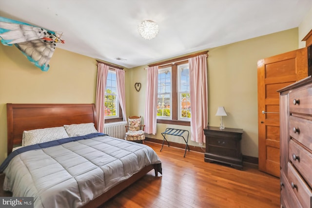 bedroom featuring hardwood / wood-style floors, visible vents, and baseboards