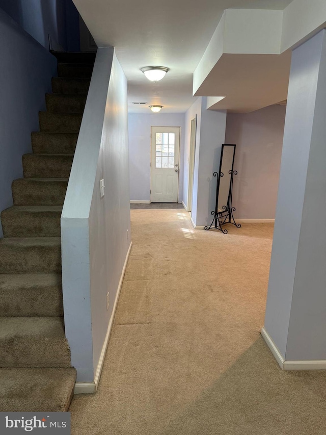 corridor featuring carpet, stairway, and baseboards