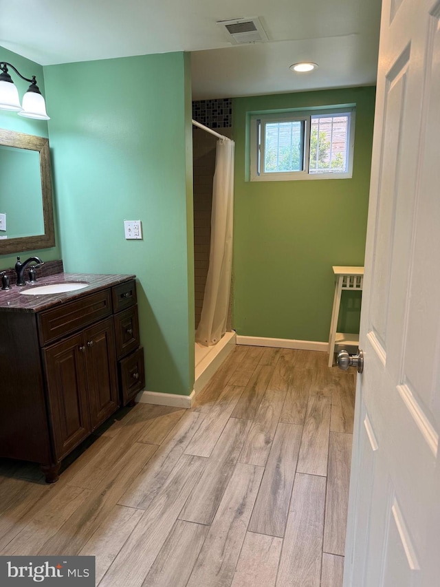 full bath with vanity, a shower stall, baseboards, and wood finished floors