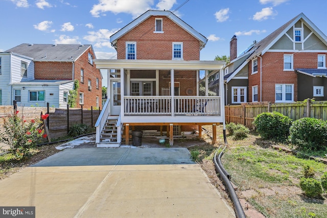 view of front facade featuring driveway, brick siding, a porch, and fence