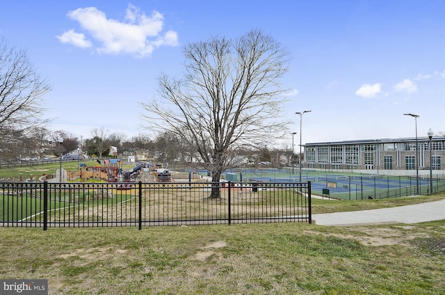 view of community with a tennis court, playground community, a lawn, and fence