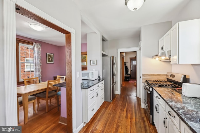 kitchen with under cabinet range hood, stainless steel appliances, dark wood-type flooring, white cabinets, and dark stone counters