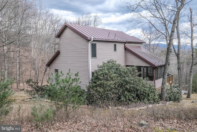 view of side of property with a standing seam roof, a sunroom, and metal roof