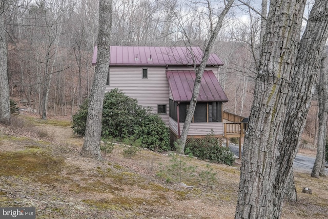 view of property exterior featuring a wooden deck, metal roof, and a standing seam roof