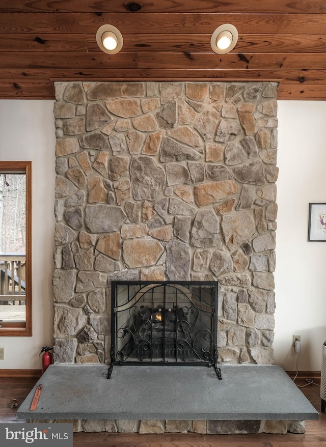 interior details with a stone fireplace, wooden ceiling, a fire extinguisher, and wood finished floors