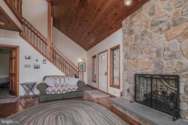 living area featuring wood finished floors, stairway, a stone fireplace, wooden ceiling, and baseboards