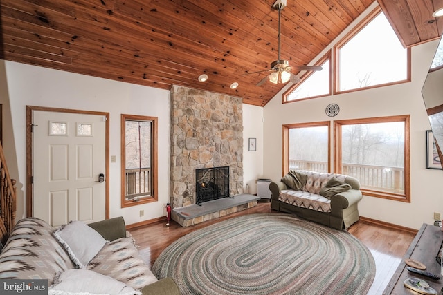 living room featuring a stone fireplace, wood ceiling, ceiling fan, and wood finished floors