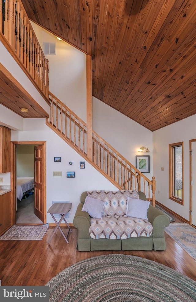 living room featuring visible vents, stairway, wood ceiling, a towering ceiling, and wood-type flooring