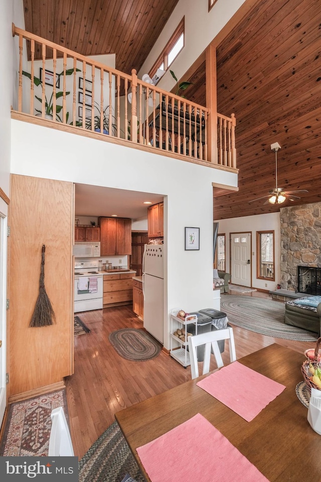 interior space with wood finished floors, a high ceiling, a fireplace, ceiling fan, and wooden ceiling