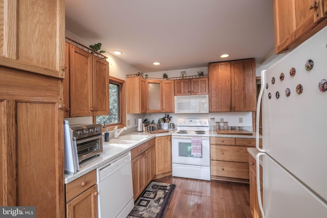 kitchen featuring white appliances, recessed lighting, wood finished floors, and a sink