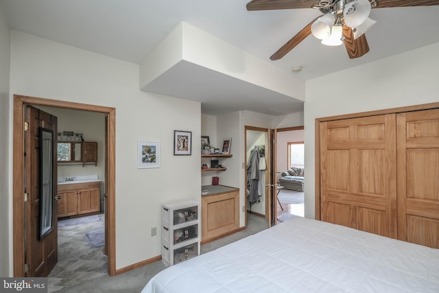 carpeted bedroom with a ceiling fan, baseboards, a closet, and a sink