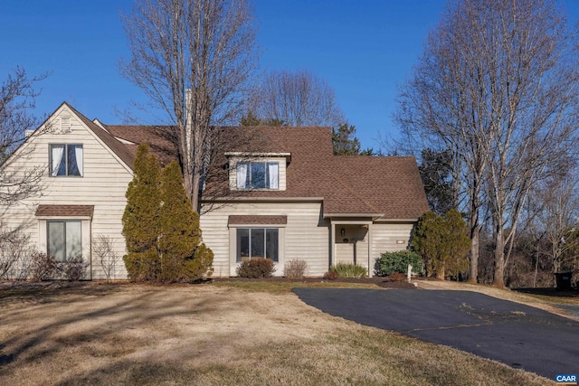 view of front of house with roof with shingles and a front lawn