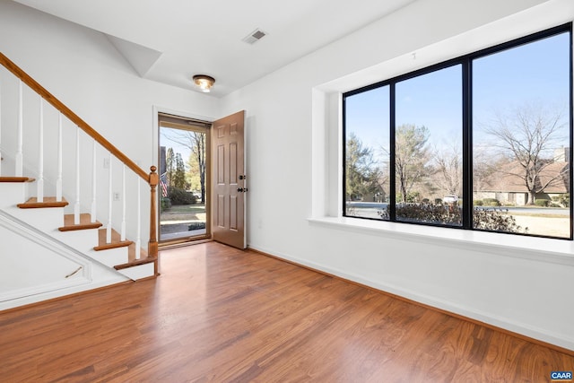 entrance foyer featuring baseboards, stairs, visible vents, and wood finished floors