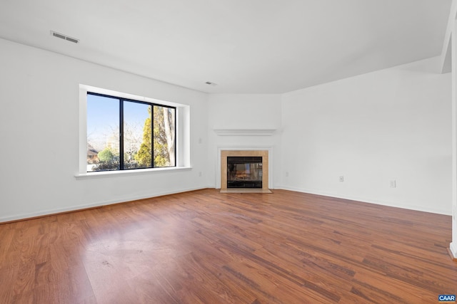 unfurnished living room with baseboards, a tiled fireplace, visible vents, and wood finished floors