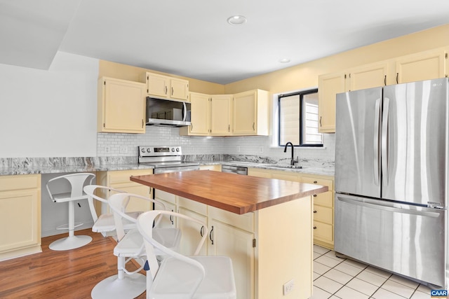 kitchen featuring a sink, stainless steel appliances, tasteful backsplash, and wood counters