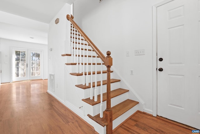 staircase featuring french doors, wood finished floors, visible vents, and baseboards