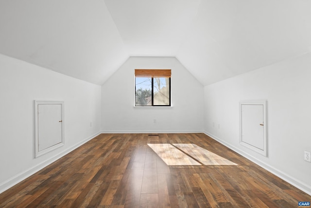 additional living space with vaulted ceiling, dark wood finished floors, and baseboards