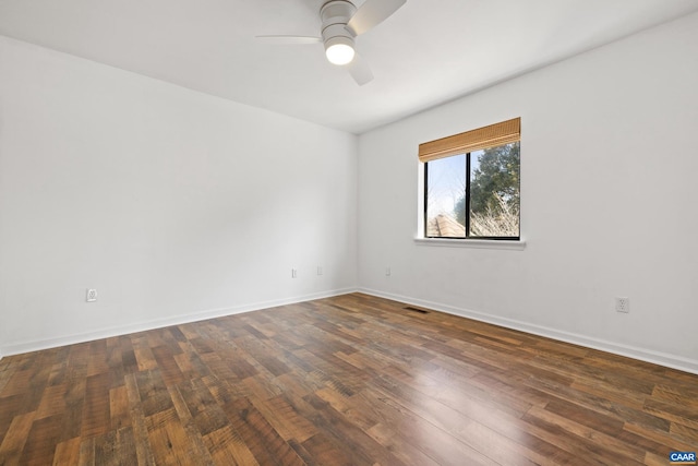 spare room with dark wood-style floors, ceiling fan, visible vents, and baseboards