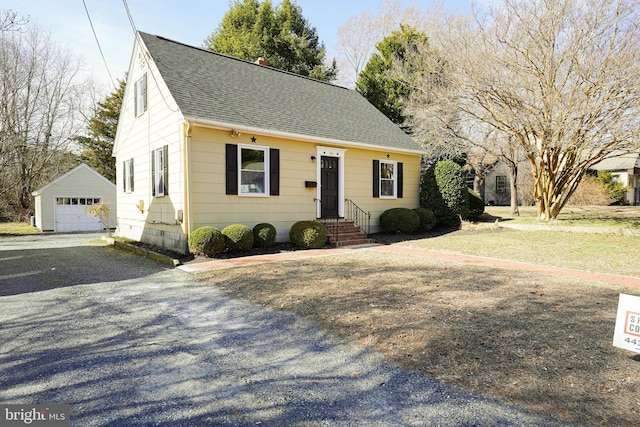 view of front of house featuring an outbuilding, roof with shingles, driveway, and a detached garage