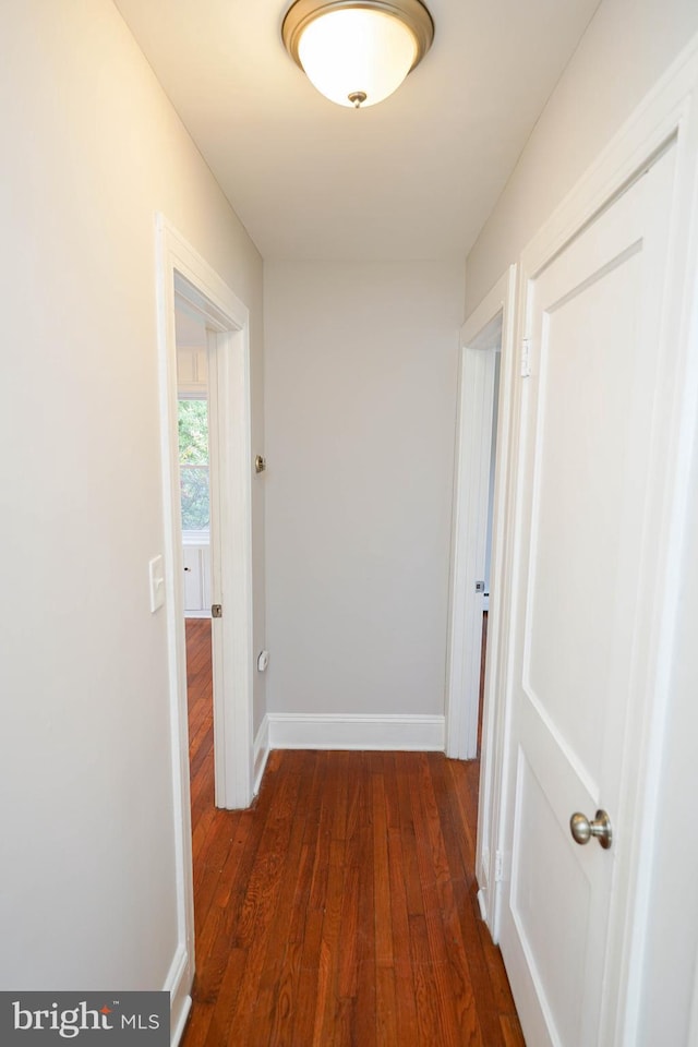 hall with dark wood-style floors and baseboards