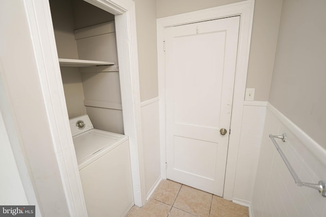 laundry area with laundry area, light tile patterned flooring, wainscoting, and washer / dryer