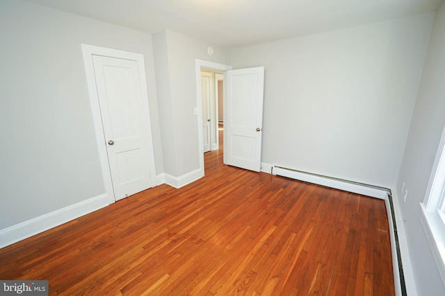 interior space featuring a baseboard radiator, baseboards, and hardwood / wood-style floors