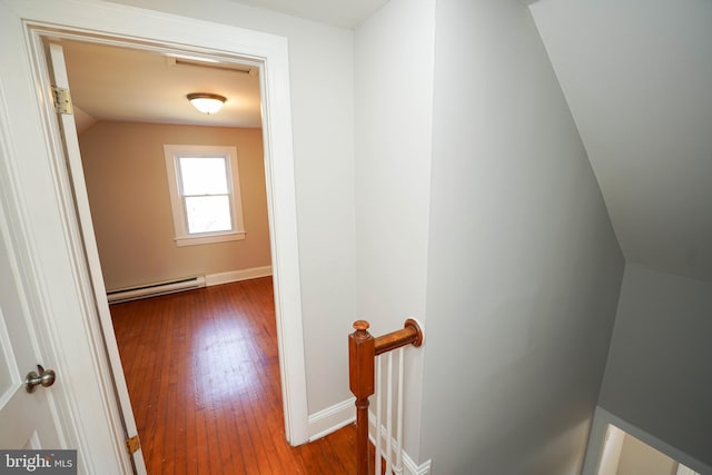 corridor with a baseboard radiator, an upstairs landing, hardwood / wood-style flooring, and baseboards