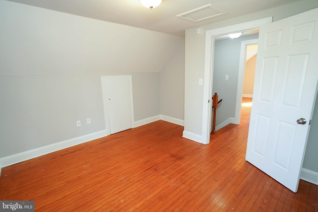 bonus room with vaulted ceiling, hardwood / wood-style flooring, attic access, and baseboards