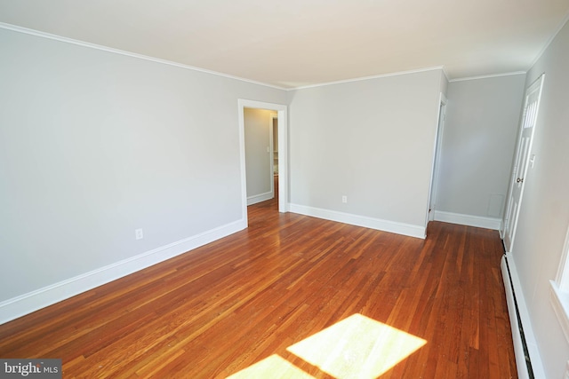 spare room with baseboards, crown molding, a baseboard heating unit, and wood finished floors