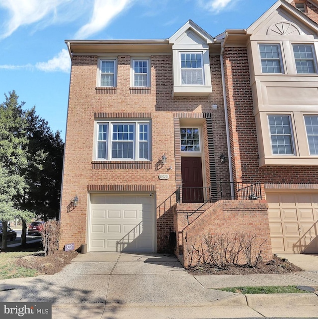 townhome / multi-family property featuring brick siding, driveway, and a garage