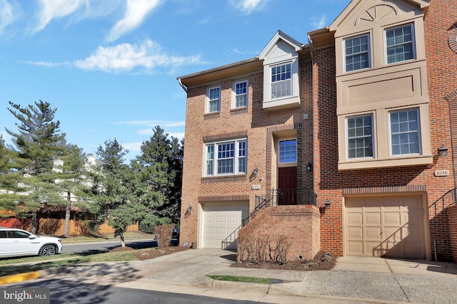 townhome / multi-family property with brick siding, an attached garage, and driveway