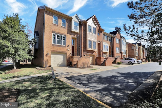 view of property with a residential view, brick siding, and an attached garage