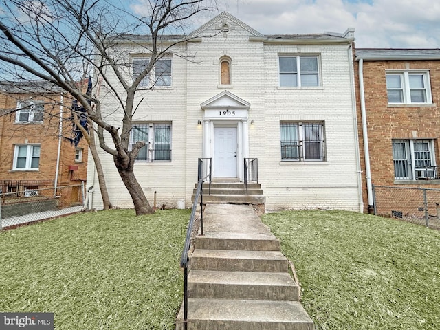 townhome / multi-family property featuring a front lawn and brick siding