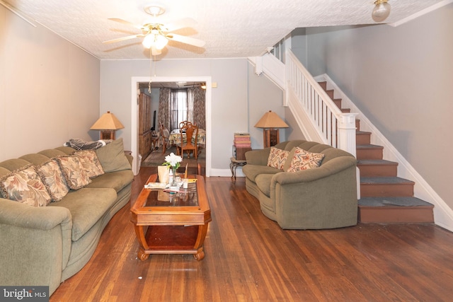 living area with a textured ceiling, ceiling fan, stairway, and wood finished floors