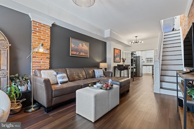 living room with dark wood-type flooring, crown molding, a notable chandelier, and stairway