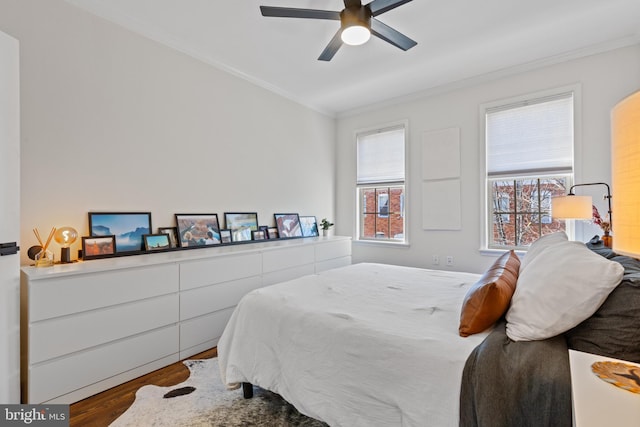 bedroom featuring ceiling fan, multiple windows, ornamental molding, and wood finished floors