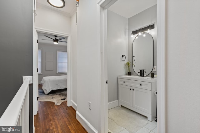 bathroom featuring baseboards, connected bathroom, ornamental molding, wood finished floors, and vanity