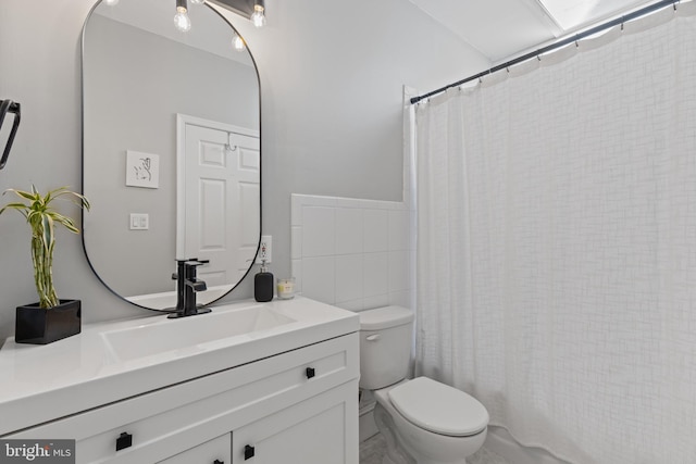 bathroom featuring toilet, curtained shower, tile walls, and vanity