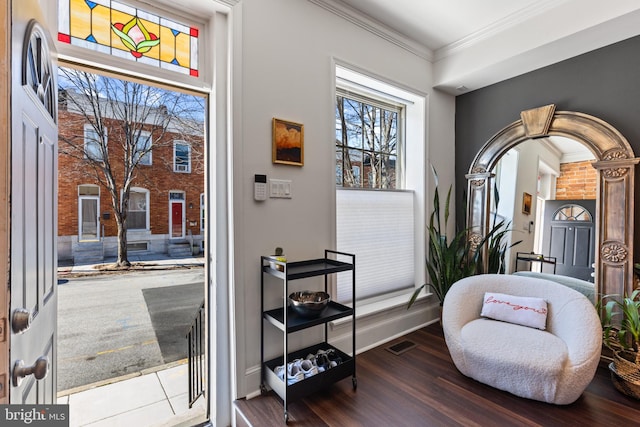 sitting room with baseboards, visible vents, crown molding, and wood finished floors