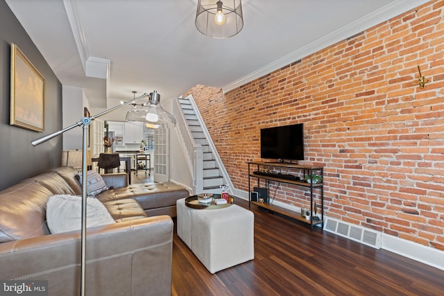 living room featuring visible vents, brick wall, ornamental molding, wood finished floors, and stairs