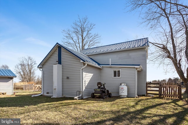 rear view of property with metal roof, a lawn, and fence