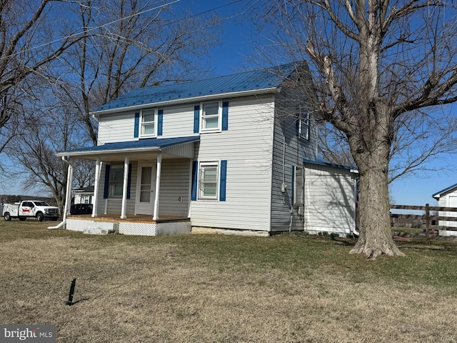 view of front of house featuring covered porch, metal roof, a front lawn, and fence