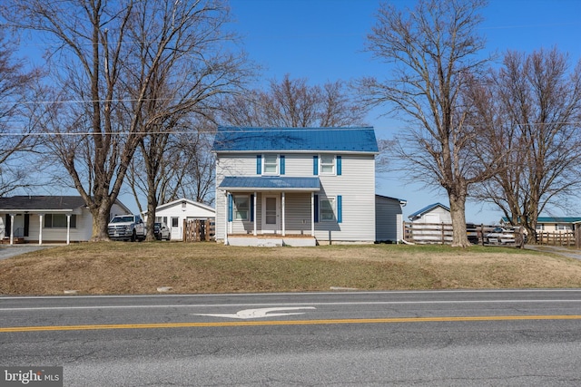 view of front of home with covered porch, metal roof, and a front lawn