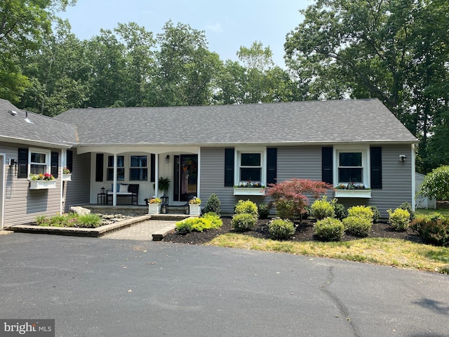 ranch-style home with covered porch and roof with shingles