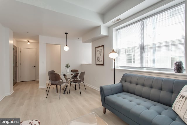 dining space featuring light wood-type flooring, visible vents, and baseboards