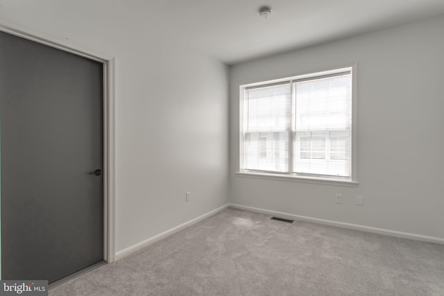 carpeted spare room featuring visible vents and baseboards