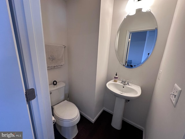 half bath featuring toilet and baseboards