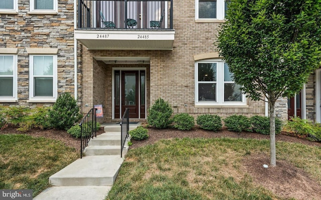 entrance to property featuring a balcony and brick siding