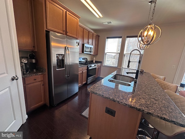 kitchen featuring a sink, stainless steel appliances, a breakfast bar, and brown cabinetry